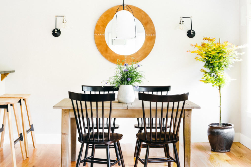 Immagine di una sala da pranzo aperta verso il soggiorno country con pareti bianche e parquet chiaro
