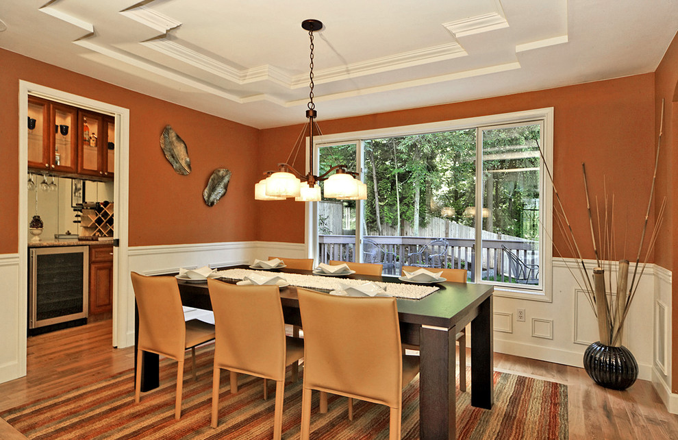 Aménagement d'une salle à manger classique fermée et de taille moyenne avec un mur orange, un sol en bois brun et aucune cheminée.