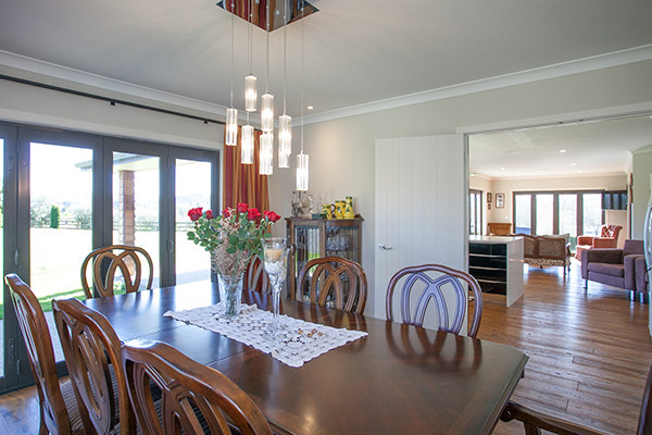 Ispirazione per una sala da pranzo aperta verso la cucina con pareti beige, pavimento in legno massello medio e pavimento marrone