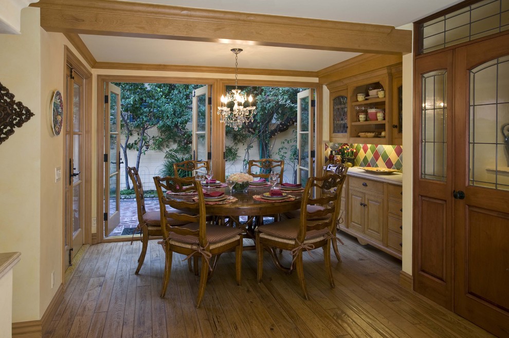 Idées déco pour une salle à manger ouverte sur la cuisine de taille moyenne avec un mur jaune, un sol en bois brun et un sol marron.