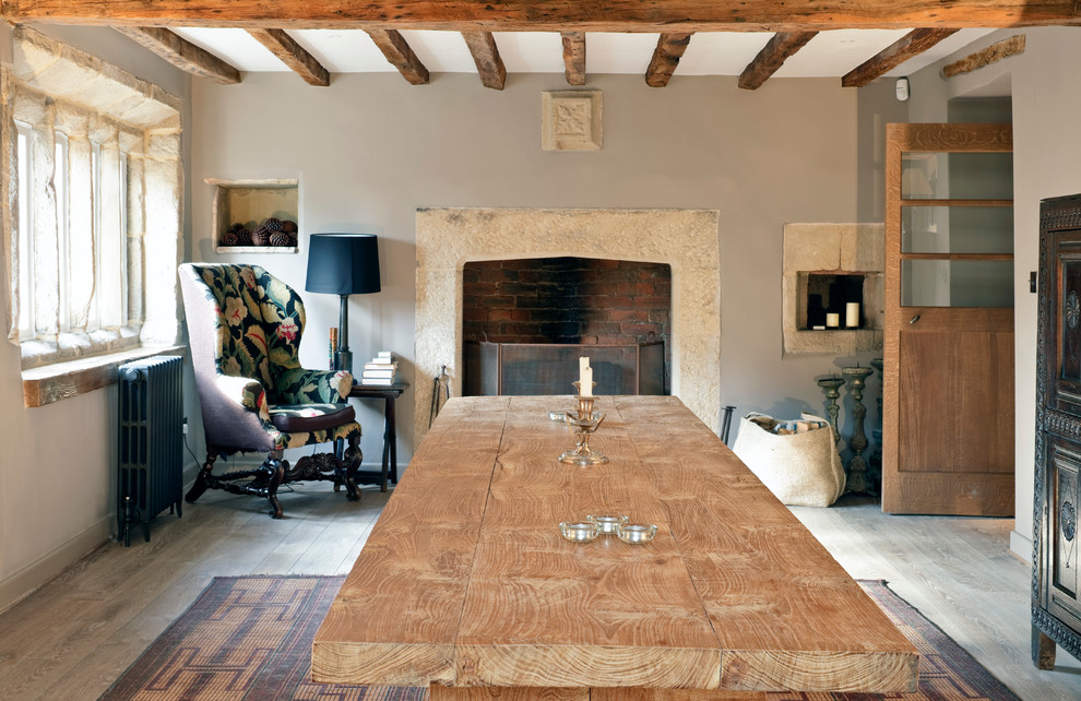 Réalisation d'une salle à manger tradition fermée avec un mur gris, un sol en bois brun, une cheminée standard et un manteau de cheminée en pierre.