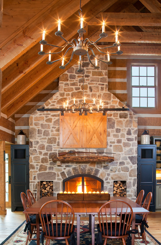 Idée de décoration pour une salle à manger ouverte sur la cuisine tradition avec un sol en bois brun, une cheminée standard et un manteau de cheminée en pierre.