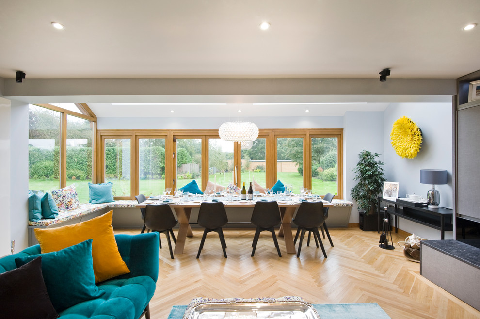 Foto di una sala da pranzo aperta verso il soggiorno minimal con pareti grigie e parquet chiaro