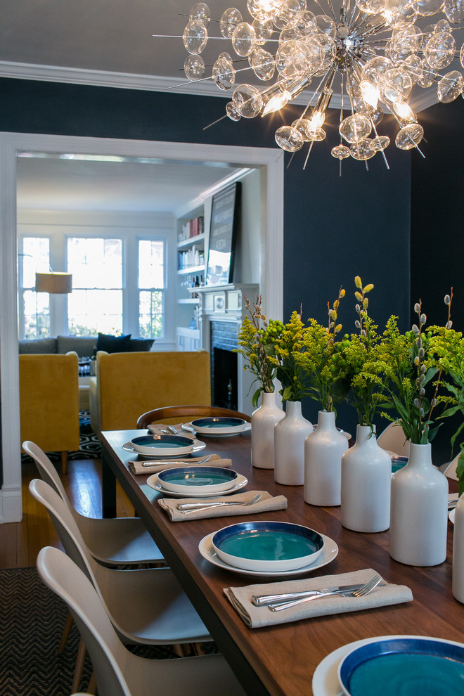 Cette photo montre une salle à manger éclectique fermée et de taille moyenne avec un mur bleu, un sol en bois brun et éclairage.