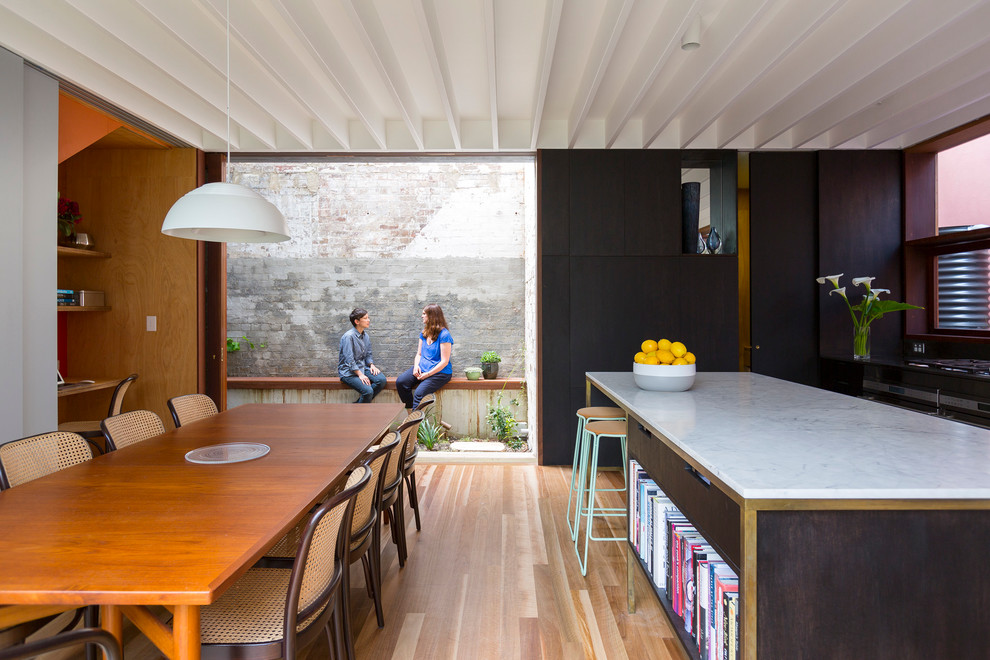 Inspiration pour une salle à manger ouverte sur la cuisine design de taille moyenne avec un mur noir, parquet clair et aucune cheminée.