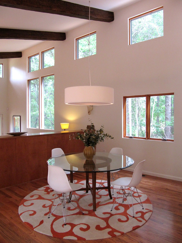 Cette image montre une salle à manger minimaliste avec un mur blanc et parquet foncé.