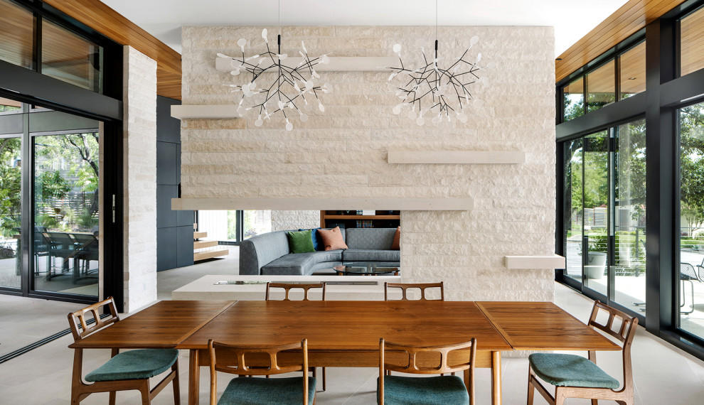 Offenes Modernes Esszimmer mit Tunnelkamin, Kaminumrandung aus Stein und grauem Boden in Austin