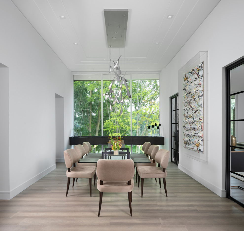 This is an example of a contemporary dining room in Detroit with white walls, no fireplace and brown floors.