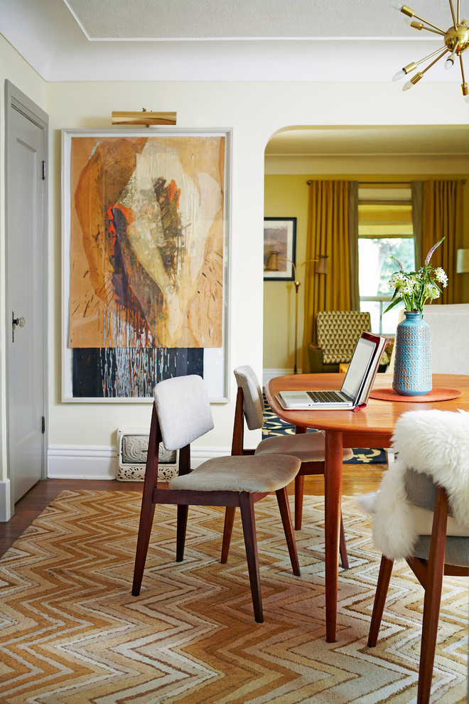 Esempio di una sala da pranzo aperta verso il soggiorno moderna con pareti gialle, pavimento in legno massello medio, nessun camino e pavimento marrone