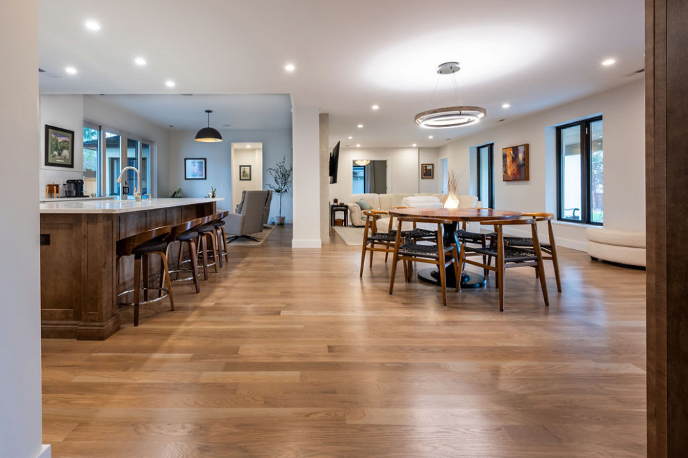 This is an example of a medium sized contemporary kitchen/dining room in Denver with white walls, medium hardwood flooring, a standard fireplace, a plastered fireplace surround and brown floors.
