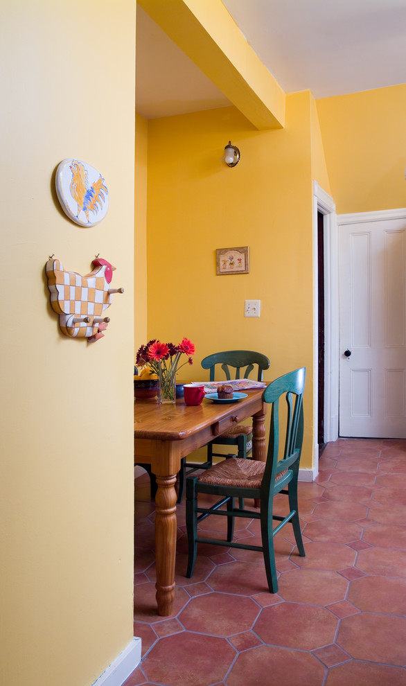 На фото: маленькая кухня-столовая в стиле кантри с полом из терракотовой плитки, желтыми стенами и коричневым полом без камина для на участке и в саду