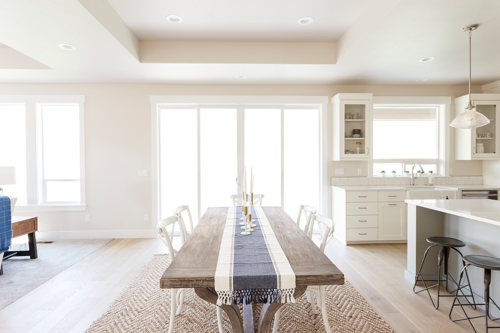 Immagine di una sala da pranzo aperta verso il soggiorno country con pareti beige, parquet chiaro e pavimento beige
