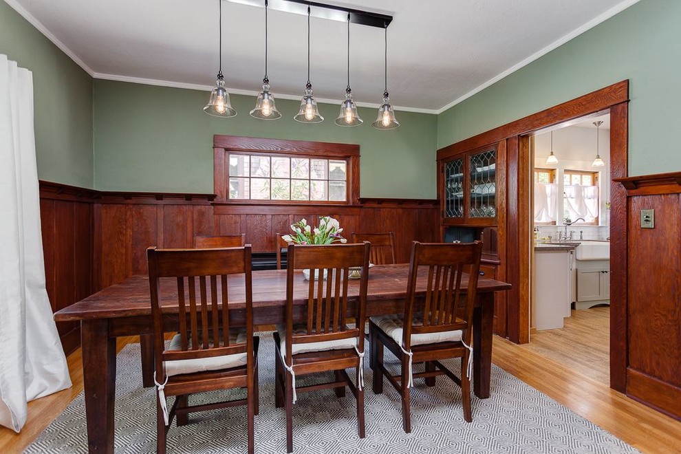 Aménagement d'une salle à manger craftsman fermée et de taille moyenne avec un mur vert, un sol en bois brun, aucune cheminée et un sol marron.