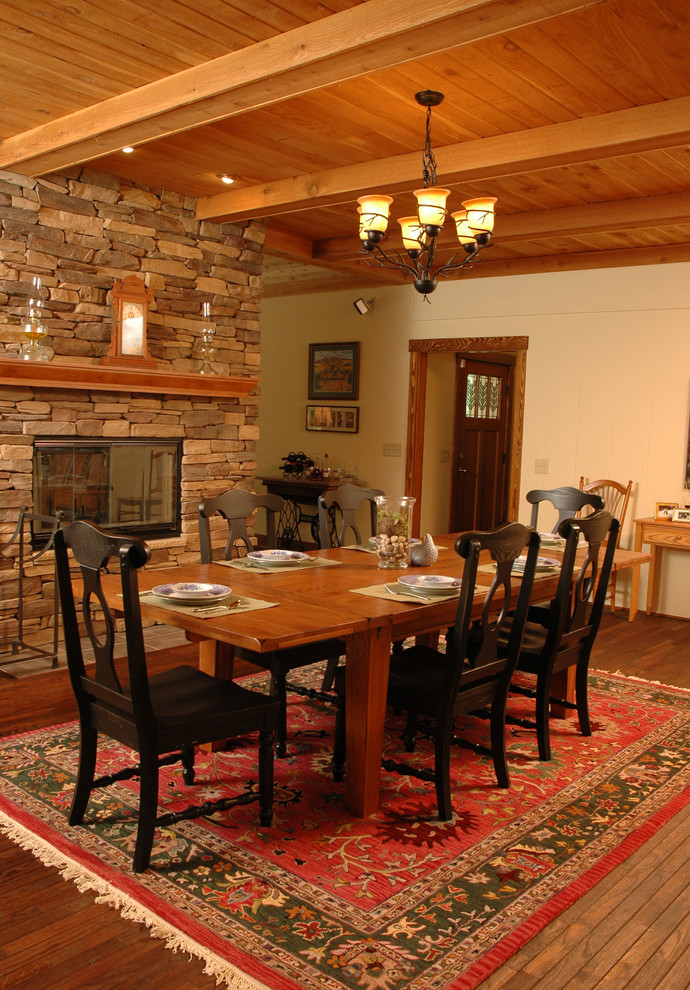 Inspiration pour une salle à manger ouverte sur le salon craftsman de taille moyenne avec un mur beige, un sol en bois brun, une cheminée double-face et un manteau de cheminée en pierre.