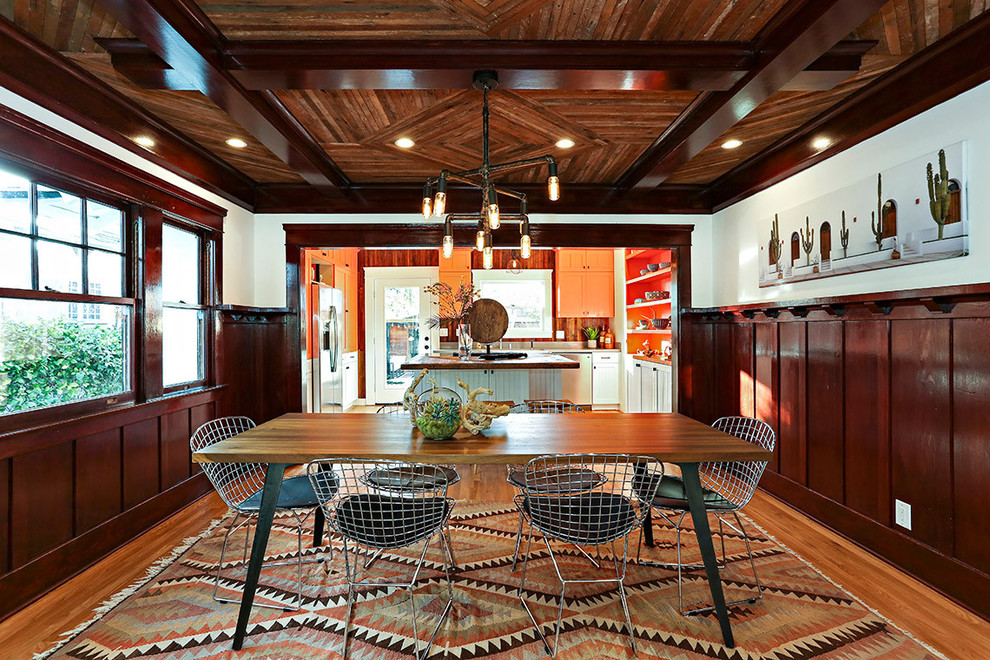 Modelo de comedor de cocina de estilo americano con paredes blancas, suelo de madera en tonos medios y suelo marrón