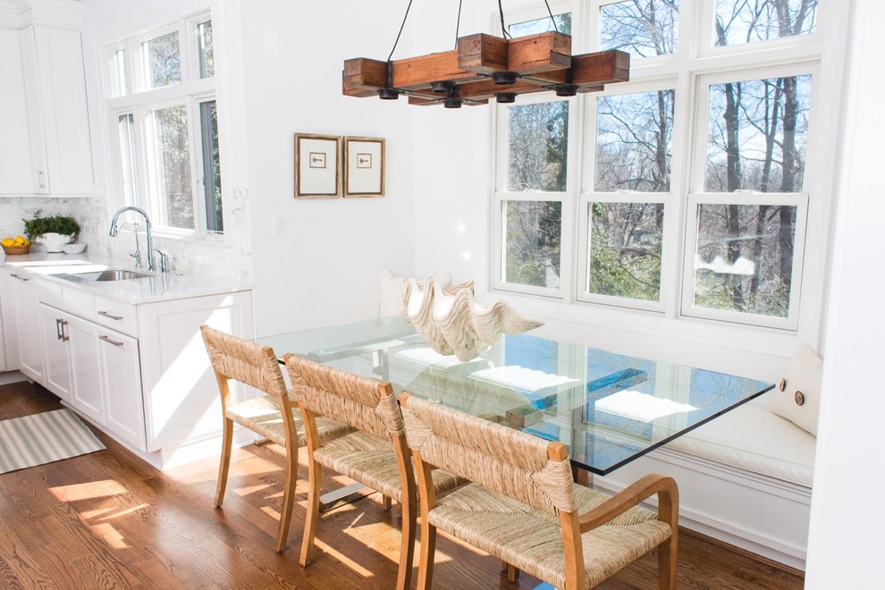 Idées déco pour une salle à manger ouverte sur la cuisine craftsman avec un mur blanc et un sol en bois brun.