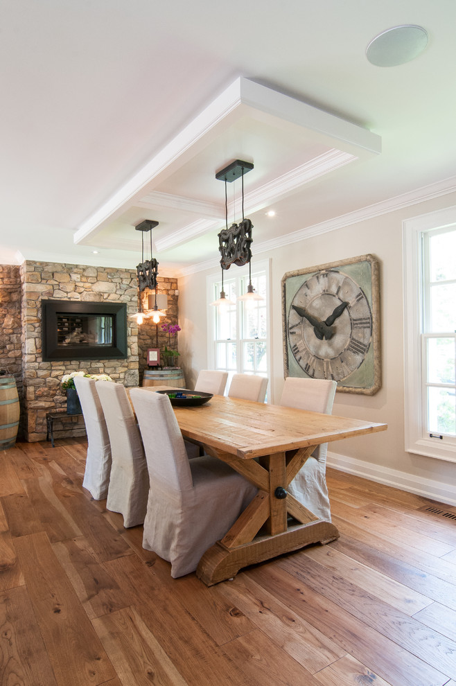Exemple d'une grande salle à manger nature avec un mur beige, un manteau de cheminée en pierre, un sol en bois brun, une cheminée standard et éclairage.