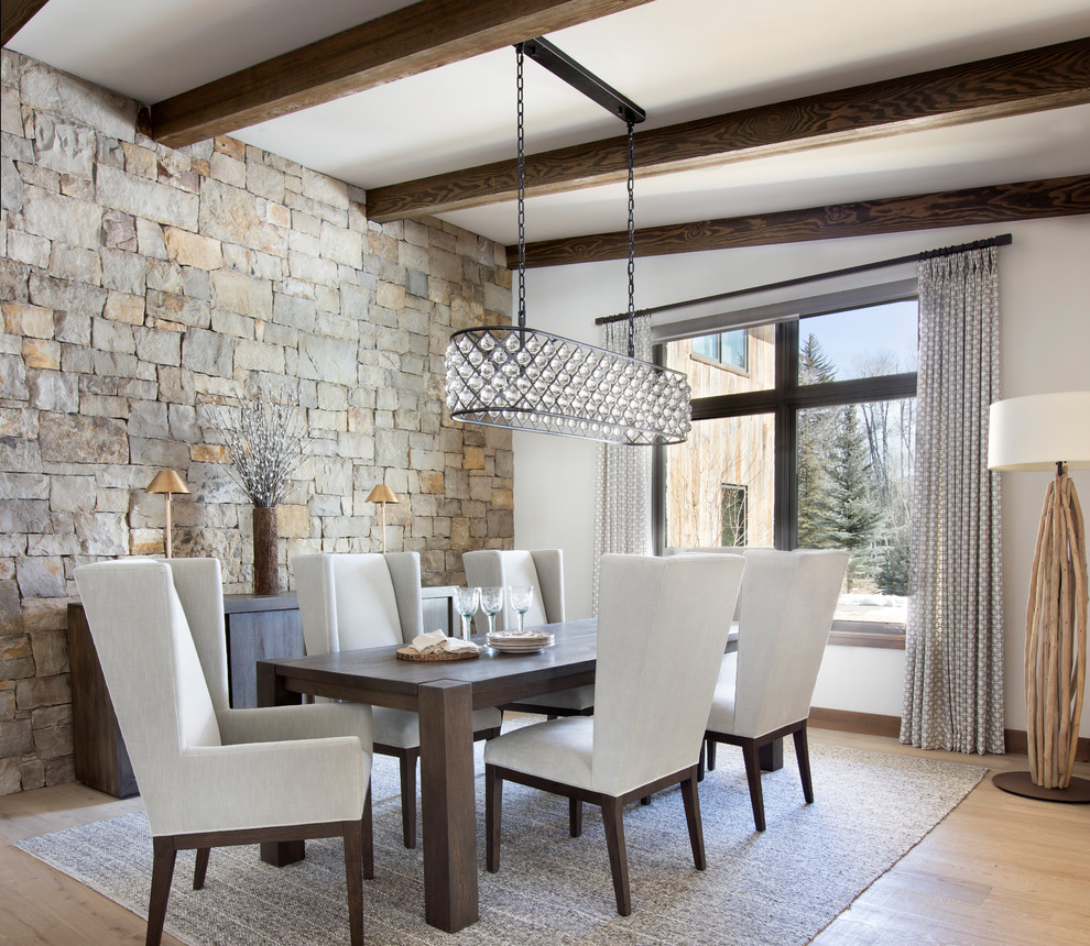 This is an example of a rustic dining room in Denver with white walls, light hardwood flooring, beige floors and feature lighting.
