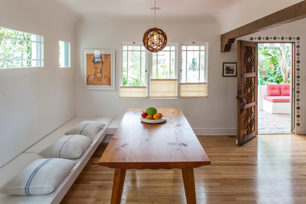 Idées déco pour une salle à manger méditerranéenne avec un mur blanc et un sol en bois brun.