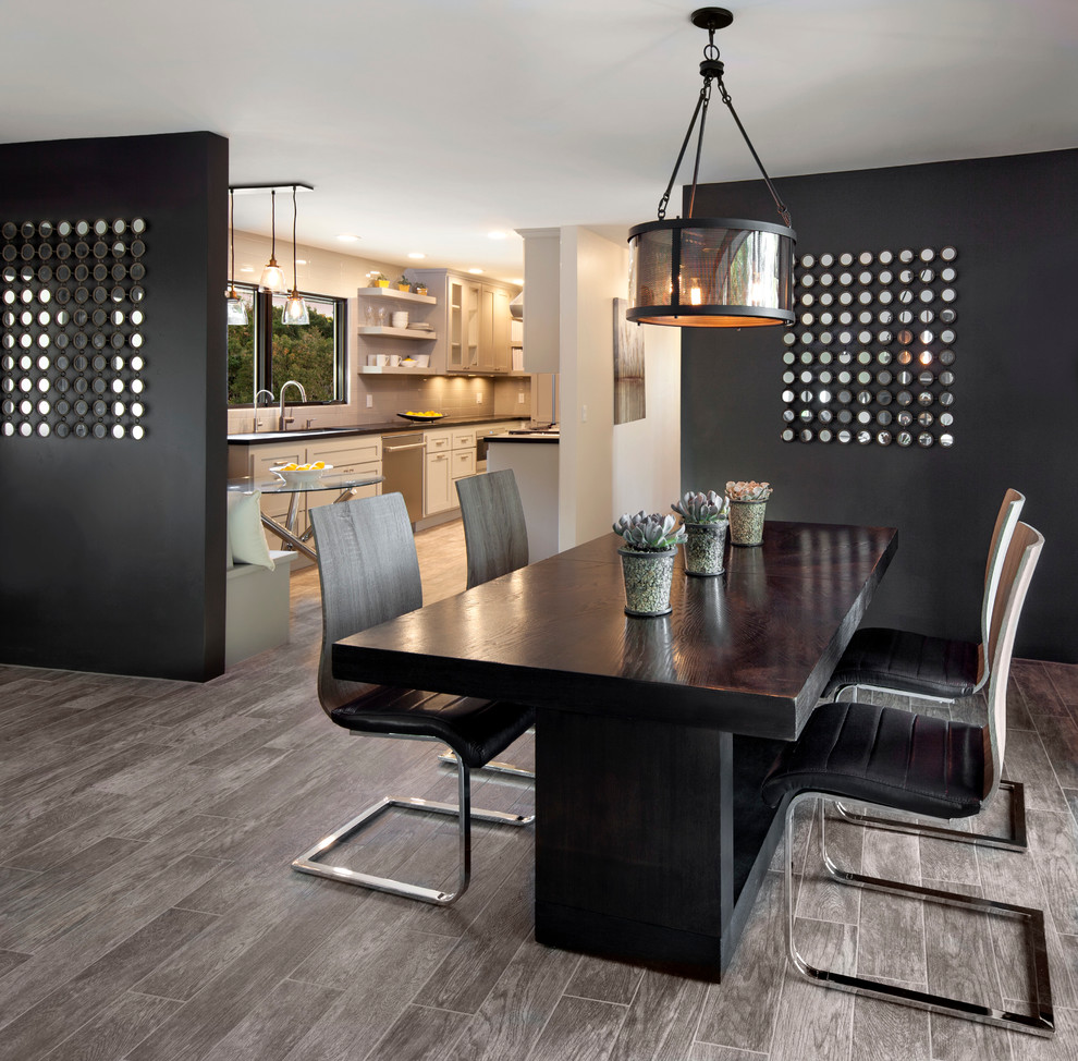 Réalisation d'une grande salle à manger ouverte sur la cuisine design avec un mur noir et un sol en bois brun.