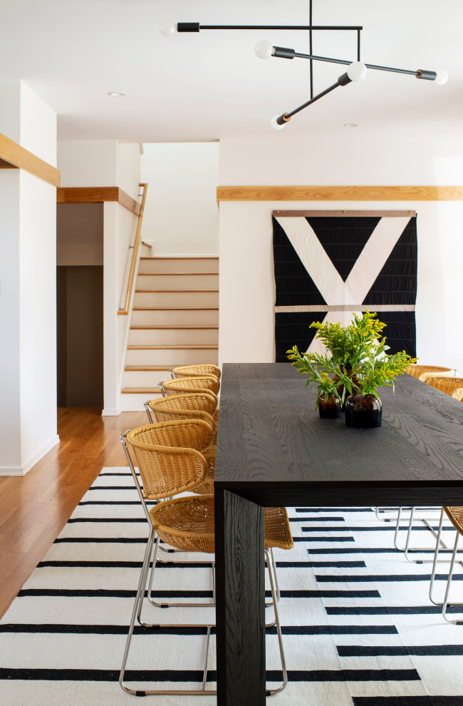 Aménagement d'une salle à manger ouverte sur la cuisine contemporaine avec un mur blanc, un sol en bois brun, une cheminée double-face et un sol marron.