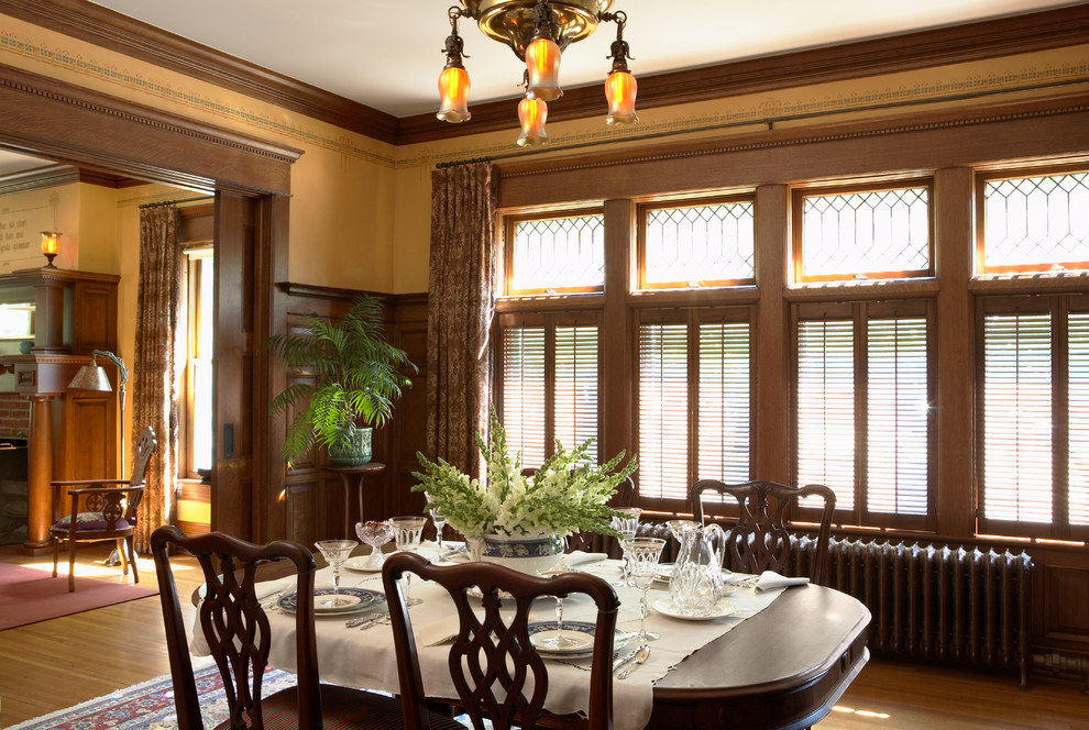 Immagine di una sala da pranzo classica con pareti gialle e parquet scuro