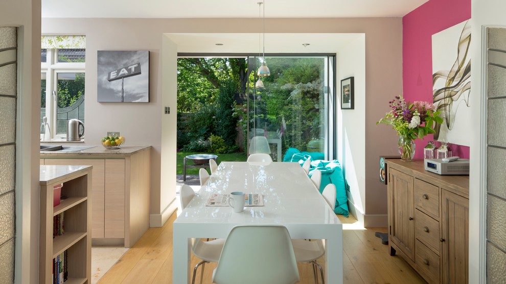 На фото: кухня-столовая среднего размера в современном стиле с белыми стенами и светлым паркетным полом без камина