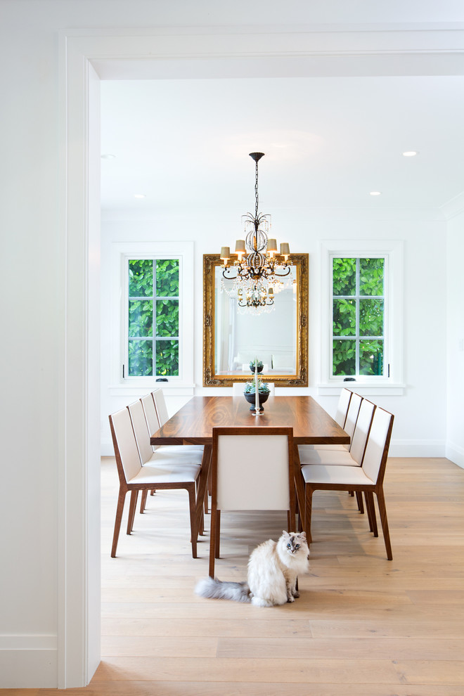 Example of a transitional medium tone wood floor enclosed dining room design in Vancouver with white walls