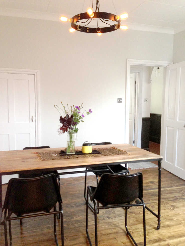 Aménagement d'une salle à manger ouverte sur la cuisine victorienne de taille moyenne avec un mur gris, un sol en bois brun, aucune cheminée et un sol marron.