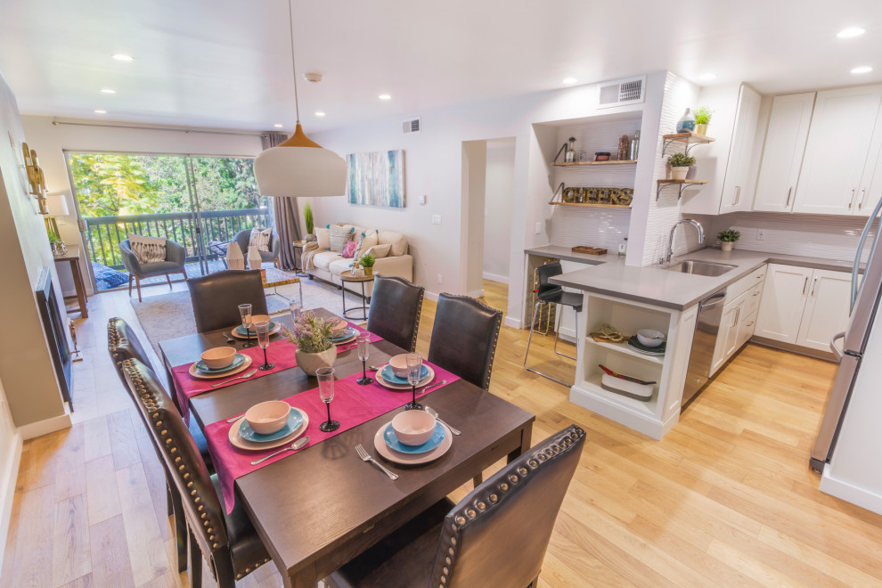 Immagine di una piccola sala da pranzo aperta verso la cucina design con pareti beige, parquet chiaro, camino classico, cornice del camino in metallo e pavimento marrone