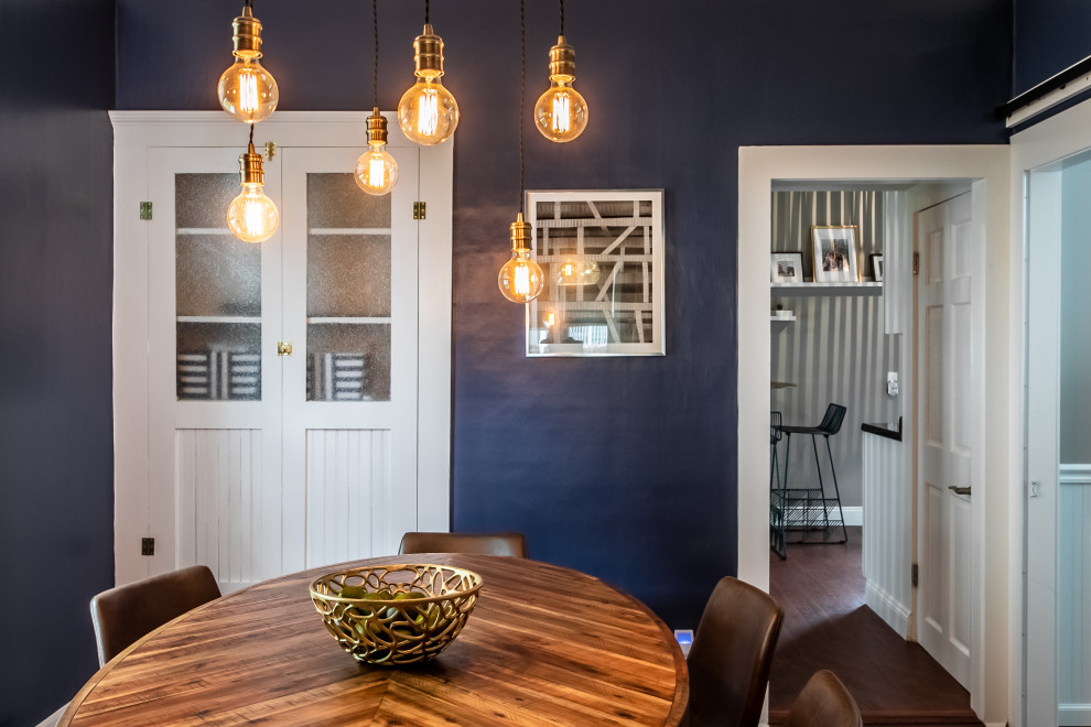 Eklektisk inredning av en liten separat matplats, med blå väggar och laminatgolv