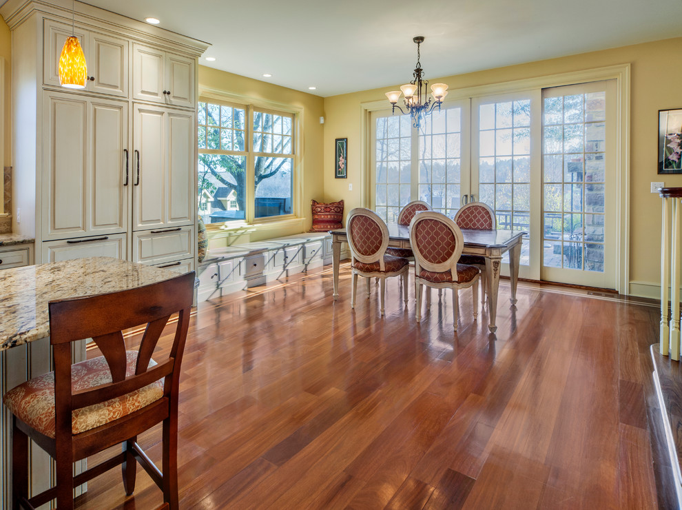 Immagine di una sala da pranzo aperta verso la cucina tradizionale di medie dimensioni con pareti gialle, pavimento in legno massello medio, nessun camino e pavimento marrone