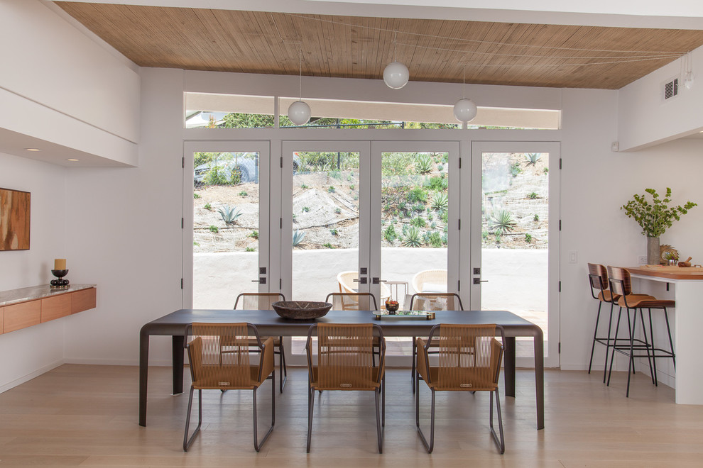 Idée de décoration pour une salle à manger ouverte sur la cuisine vintage avec un mur blanc et parquet clair.