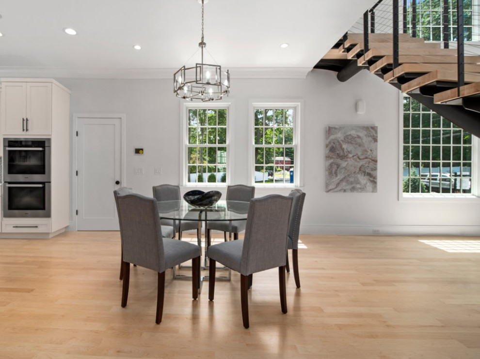 Large modern dining room in Boston with banquette seating, grey walls and light hardwood flooring.