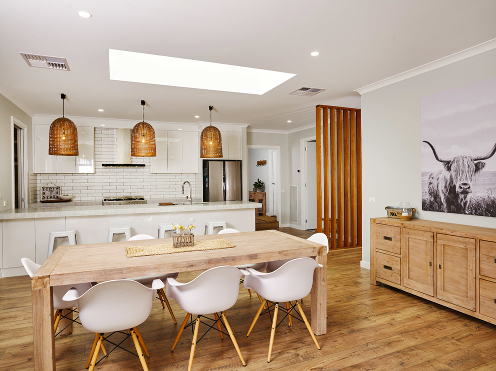 Exemple d'une grande salle à manger ouverte sur la cuisine tendance avec un mur gris, sol en stratifié et un sol marron.