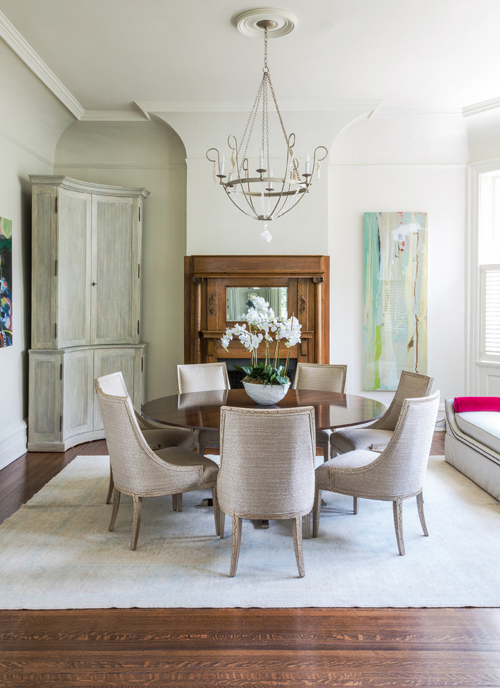 Classic dining room in New Orleans with white walls, medium hardwood flooring and a standard fireplace.