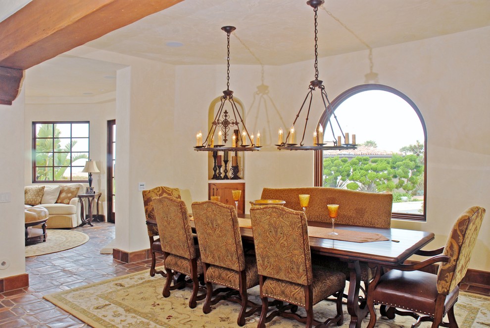 На фото: большая кухня-столовая в средиземноморском стиле с белыми стенами, полом из терракотовой плитки и коричневым полом с