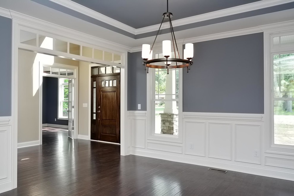 Cette photo montre une grande salle à manger craftsman fermée avec un mur gris, parquet foncé et aucune cheminée.