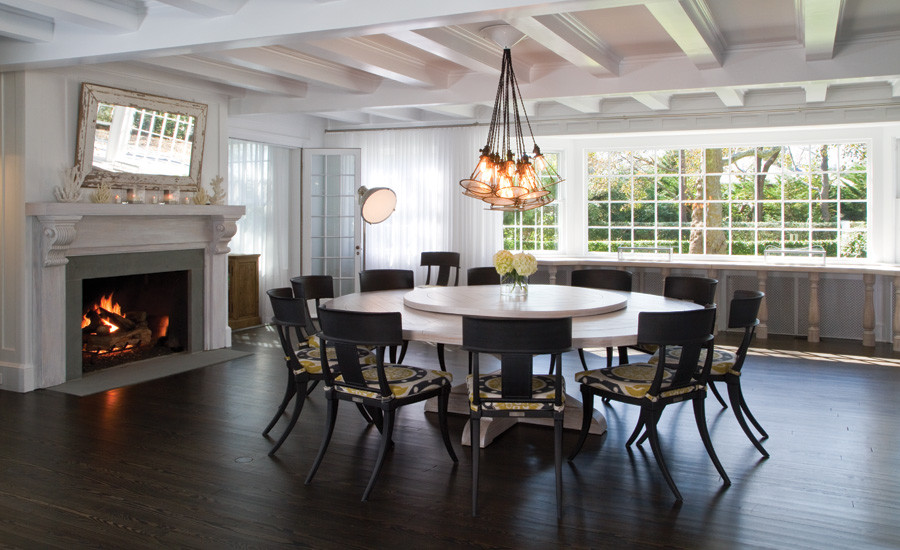 This is an example of an expansive beach style open plan dining room in New York with white walls, dark hardwood flooring, a standard fireplace and a stone fireplace surround.