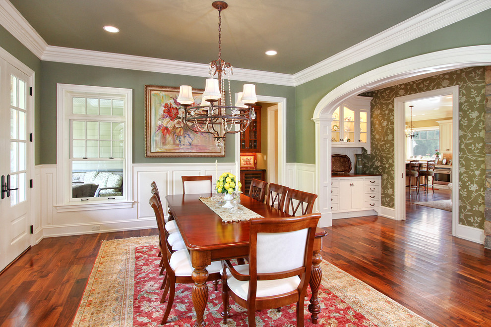 Inspiration pour une salle à manger traditionnelle fermée avec un mur vert et un sol en bois brun.