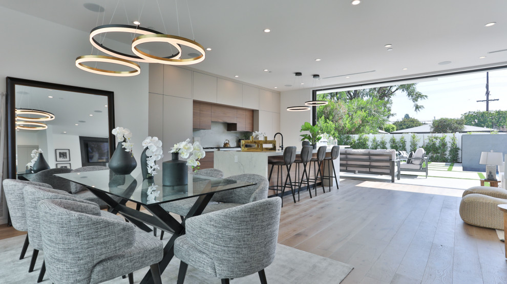 This is an example of a large modern kitchen/dining room in Los Angeles with white walls, light hardwood flooring and beige floors.