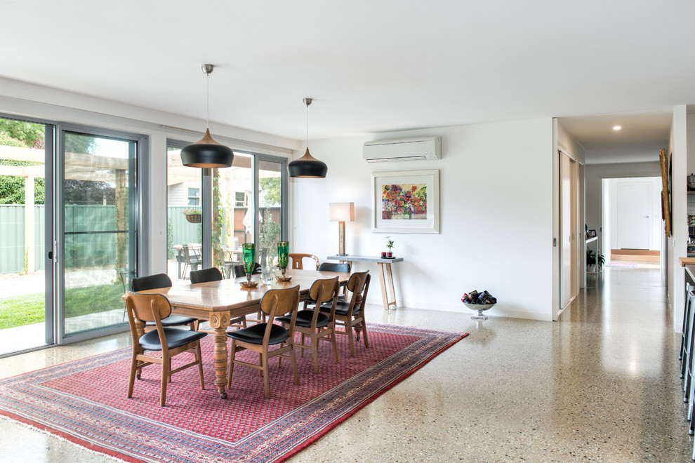 Modelo de comedor minimalista abierto con paredes blancas, suelo de cemento y suelo multicolor