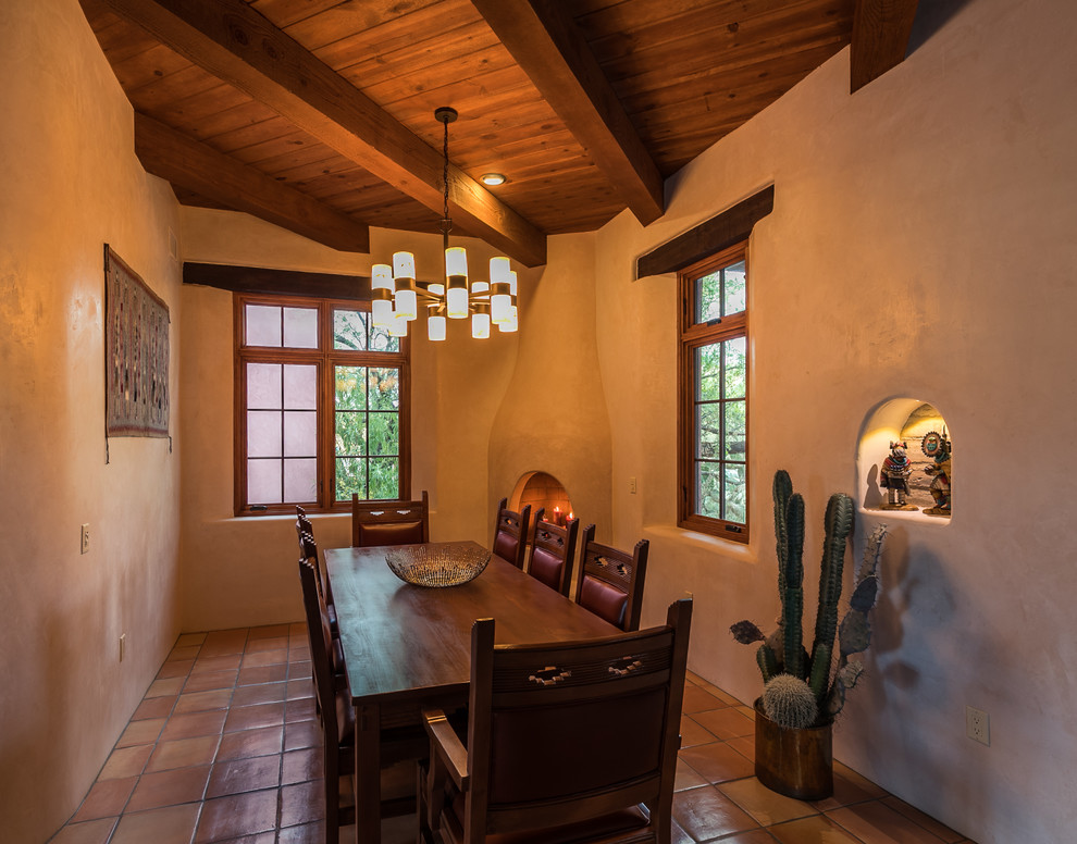 Idée de décoration pour une salle à manger sud-ouest américain avec un mur blanc, tomettes au sol, une cheminée d'angle et un sol rose.