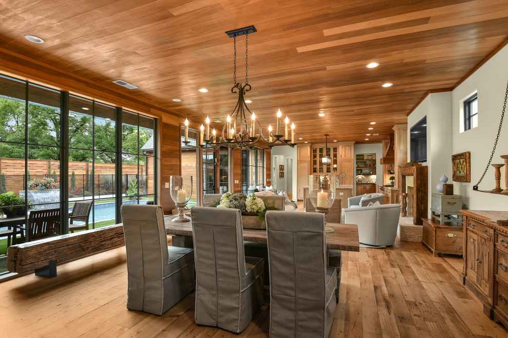 Réalisation d'une grande salle à manger ouverte sur le salon champêtre en bois avec un mur blanc, un sol en bois brun, une cheminée standard, un manteau de cheminée en bois et un plafond en bois.