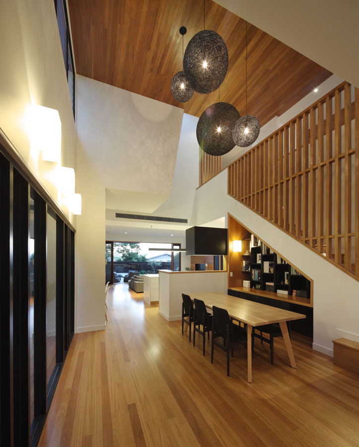 Cette photo montre une grande salle à manger ouverte sur le salon tendance avec un mur blanc et un sol en bois brun.