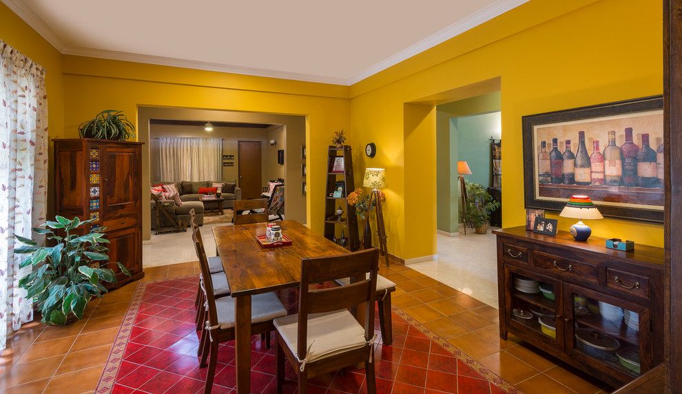 Cette image montre une salle à manger bohème de taille moyenne et fermée avec un mur jaune, un sol en carrelage de céramique et un sol multicolore.