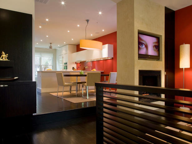 На фото: кухня-столовая среднего размера в современном стиле с красными стенами, темным паркетным полом, двусторонним камином, фасадом камина из штукатурки и коричневым полом с