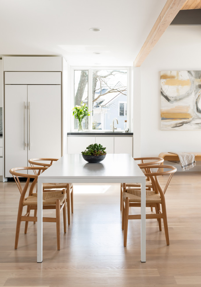 Imagen de comedor actual abierto con paredes blancas, suelo de madera clara y suelo beige