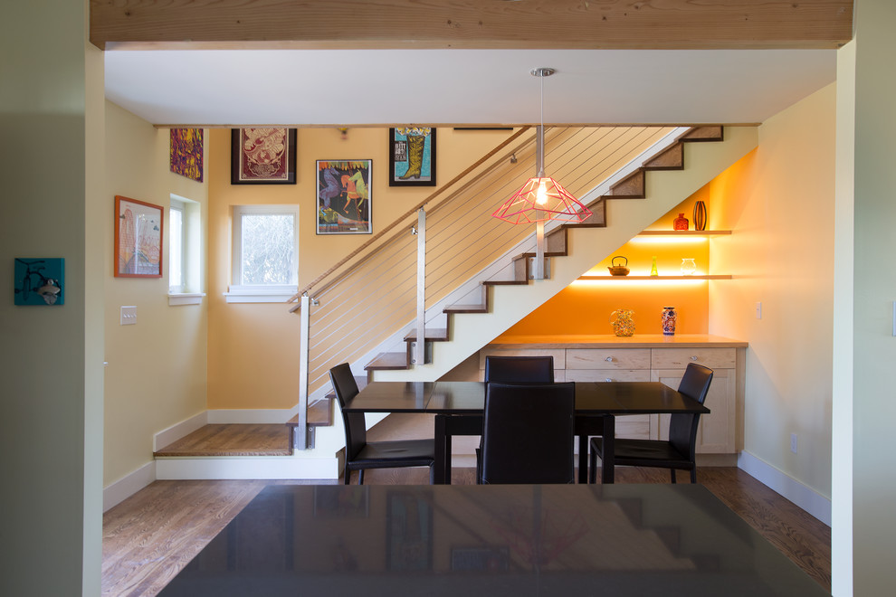 Ispirazione per una sala da pranzo aperta verso la cucina di medie dimensioni con pareti arancioni, parquet chiaro e pavimento marrone