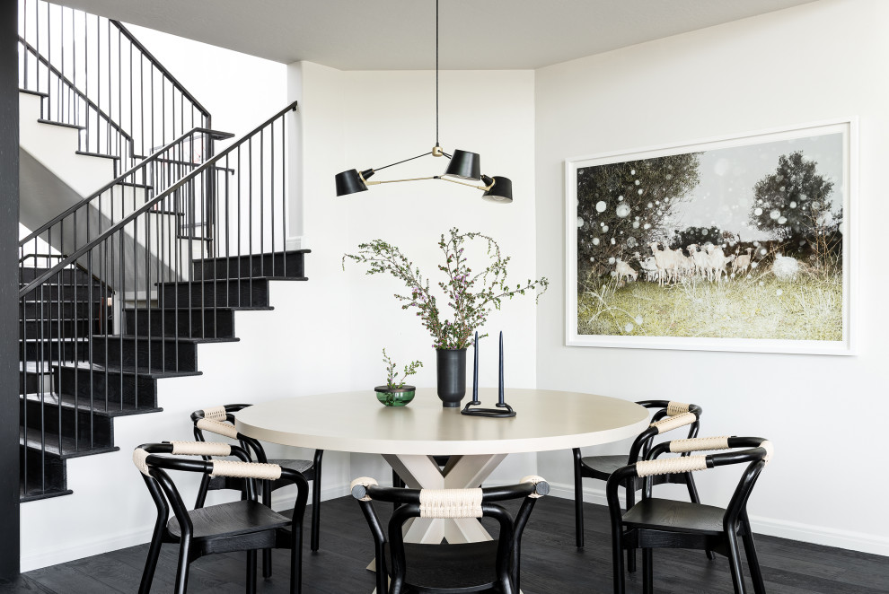 Cette image montre une salle à manger traditionnelle avec un mur blanc, parquet foncé et un sol noir.